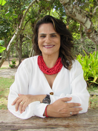Andrea Azevedo com um cachecol vermelho e blusa branca sorrindo