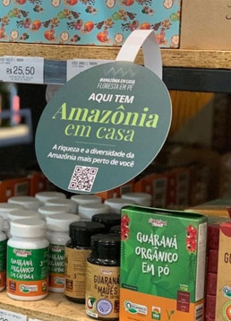 produtos em uma prateleira de mercado com uma placa em cima com os dizeres aqui tem Amazônia em Casa